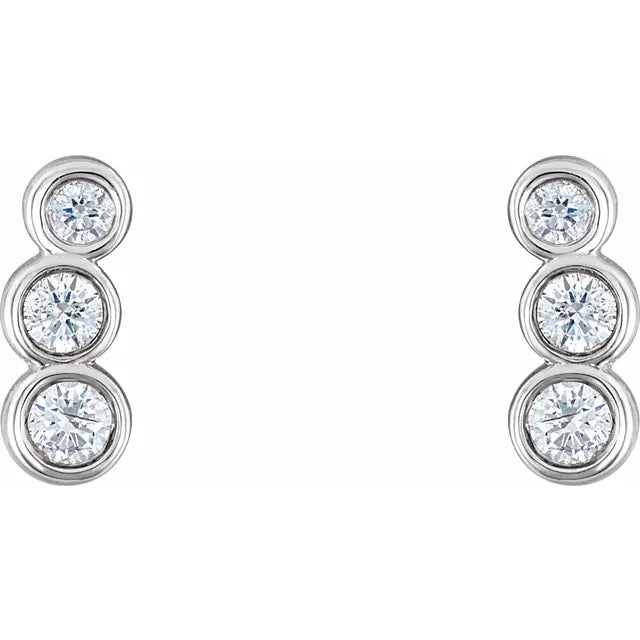 Pair of white gold diamond ear climbers with three stones in a bezel setting