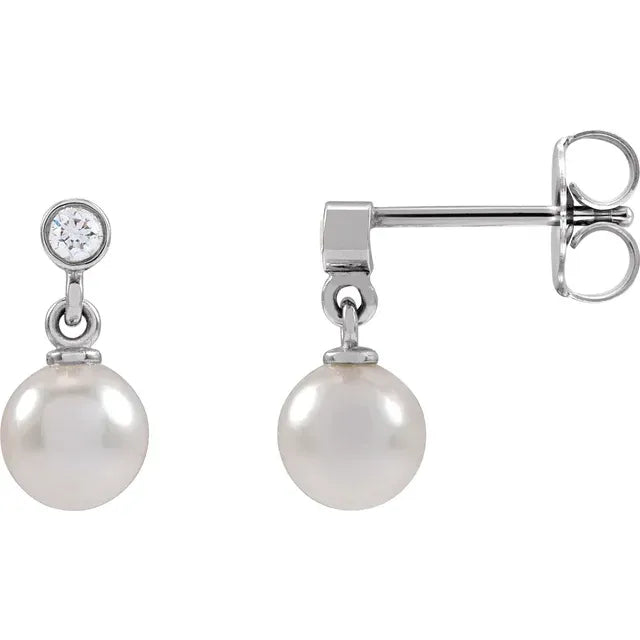 Silver pearl and diamond drop earrings on a white background