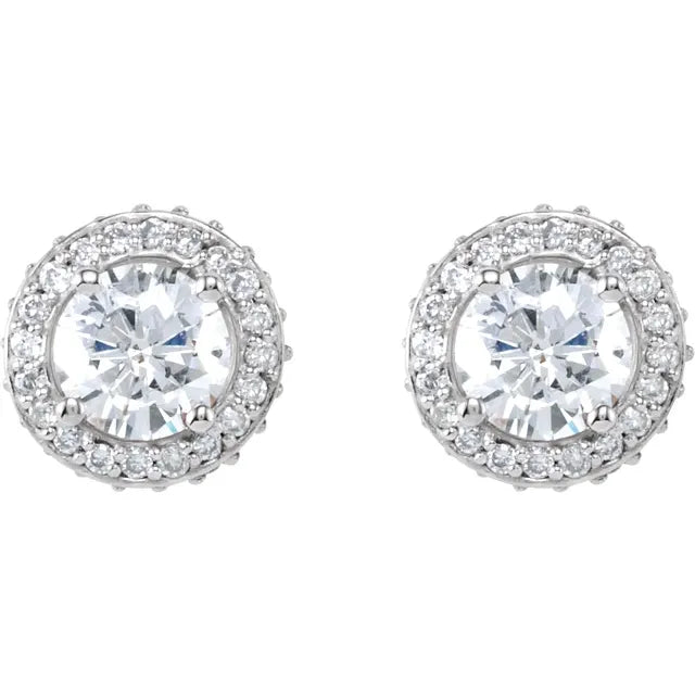 Pair of silver stud earrings, each with a central diamond surrounded by a halo of smaller diamonds. The background is white.