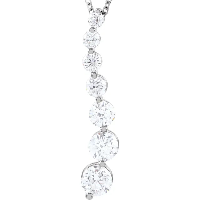 Silver necklace with a pendant featuring a line of seven round diamonds of varying sizes, arranged in a staggered pattern. The background is white.