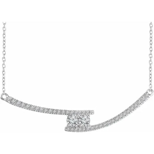 White gold necklace with a pendant featuring two round diamonds set on intersecting curved bands of diamonds. The background is white.