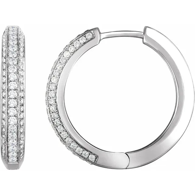 Pair of silver hoop earrings covered in diamonds. The background is white.