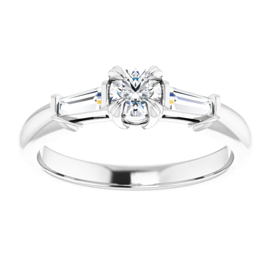 White gold ring with a central round diamond flanked by two baguette-cut diamonds. The background is white.