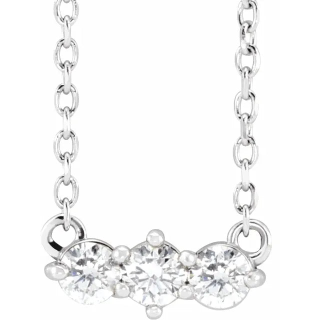 White gold three-stone diamond necklace on a white background.